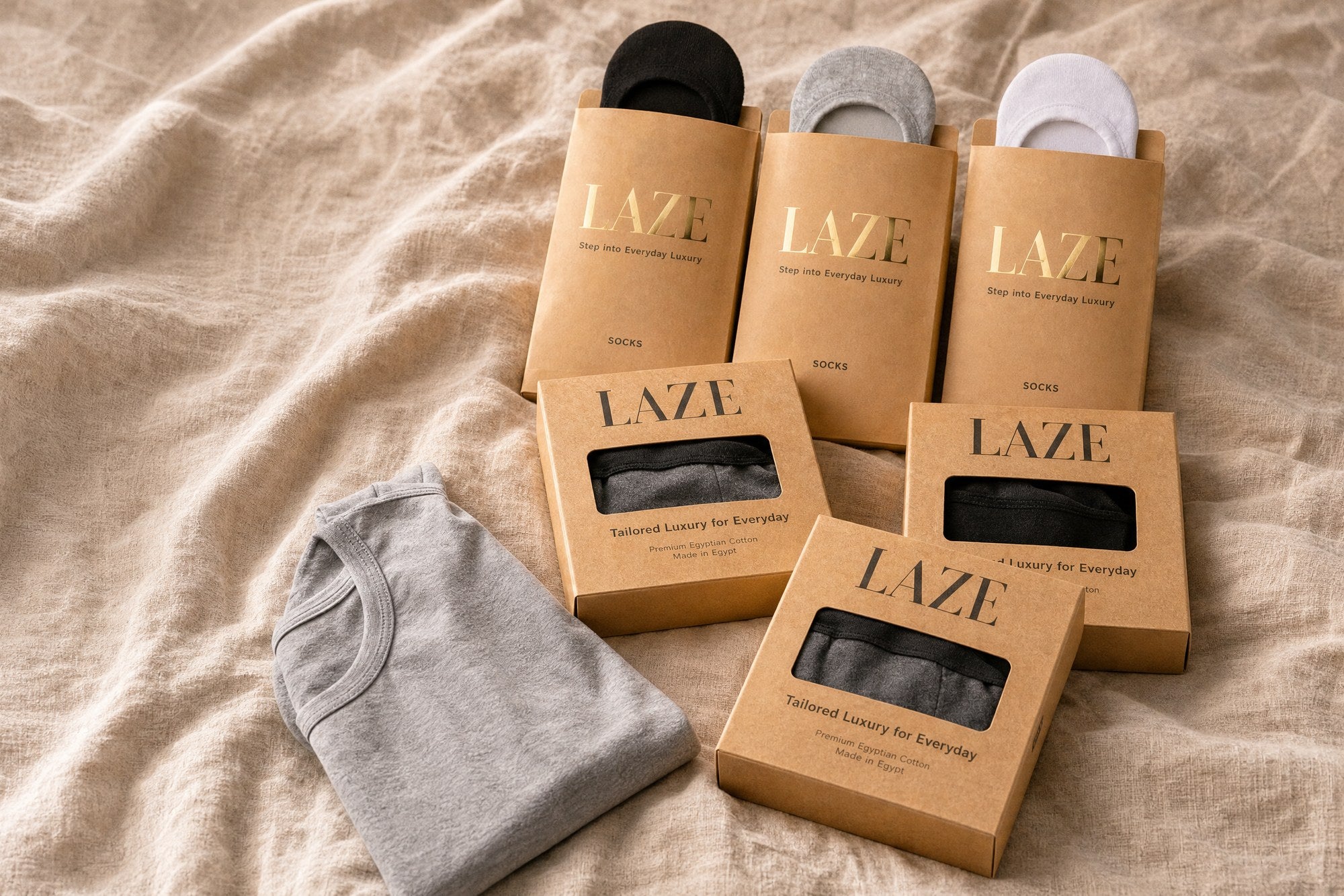 Laze Inner Serenity essentials: kraft boxes, sock packs and a grey tee on linen
